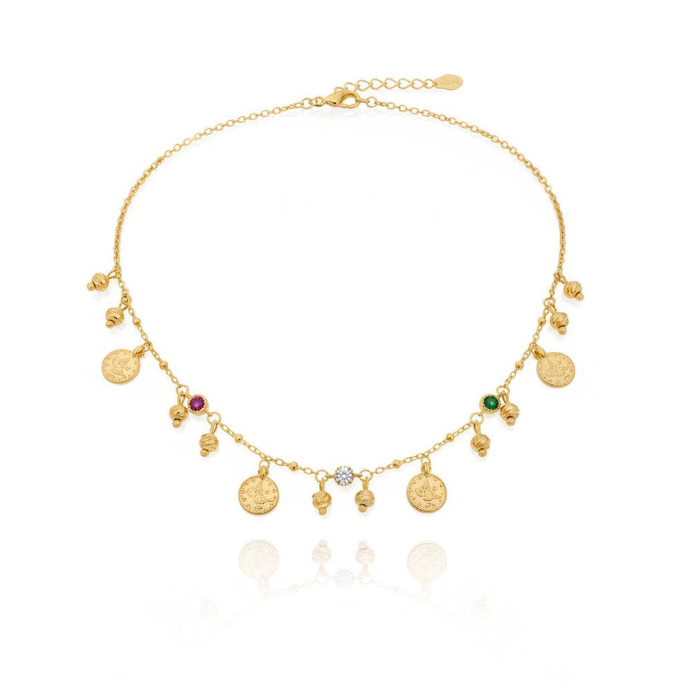 A delicate gold chain necklace with multiple dangling coin charms, small bead drops, and three colorful gemstone accents (red, green, and clear), displayed on a clean white background with a soft reflection below.